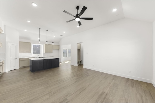 kitchen featuring light wood-style floors, a center island, vaulted ceiling, and a sink