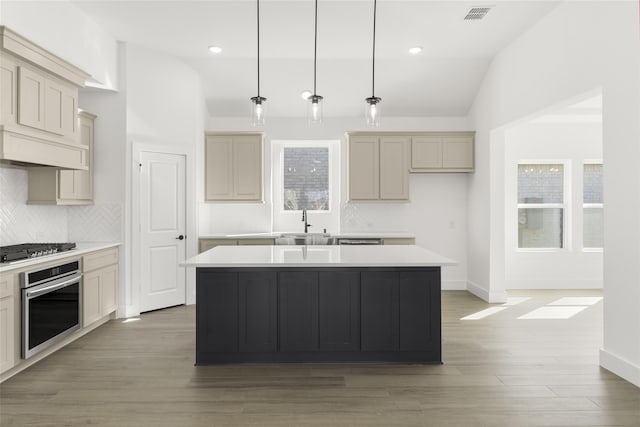 kitchen featuring gas stovetop, visible vents, vaulted ceiling, a kitchen island, and oven
