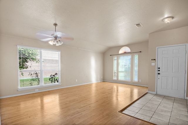 entrance foyer featuring ceiling fan, a textured ceiling, vaulted ceiling, and light wood-type flooring