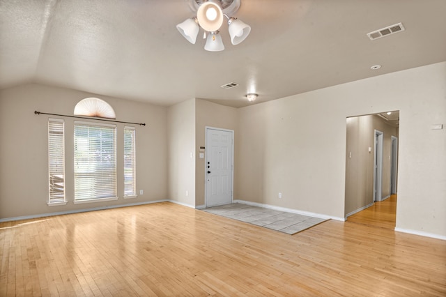 unfurnished room featuring vaulted ceiling and light wood-type flooring