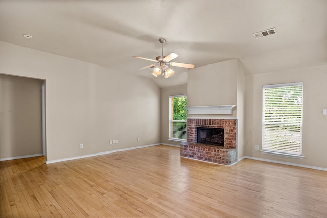 unfurnished living room featuring light hardwood / wood-style floors, a healthy amount of sunlight, a brick fireplace, and ceiling fan