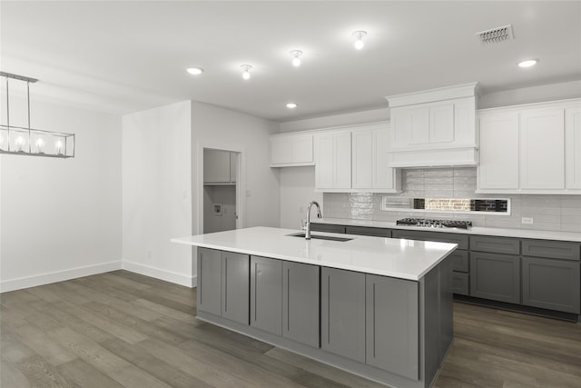 kitchen with premium range hood, white cabinetry, sink, and an island with sink