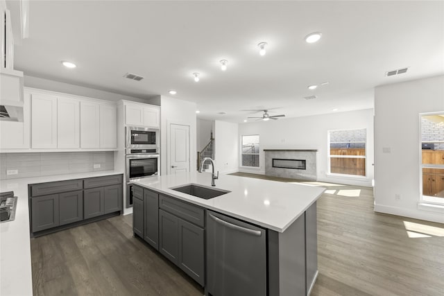 kitchen featuring gray cabinetry, a kitchen island with sink, sink, dark hardwood / wood-style floors, and stainless steel appliances