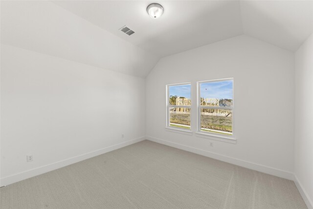 bonus room with light colored carpet and vaulted ceiling