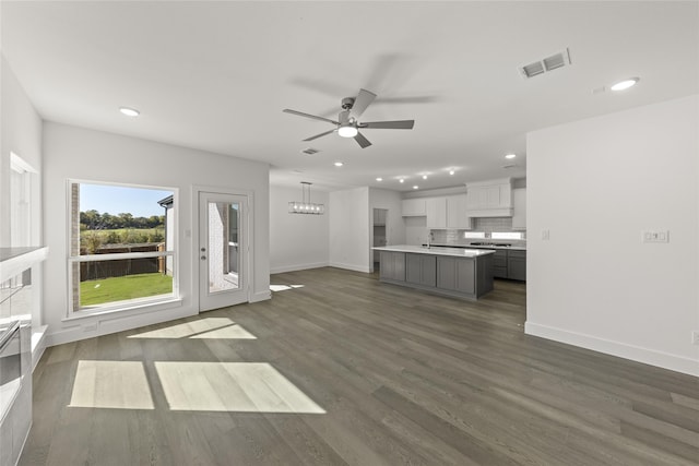 unfurnished living room featuring sink, dark wood-type flooring, and ceiling fan with notable chandelier