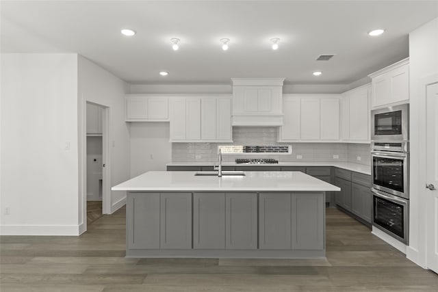 8108 Caprock Trl, Rowlett, TX 75089 - kitchen featuring stainless steel appliances, light wood finished floors, light countertops, a kitchen island with sink, and tasteful backsplash