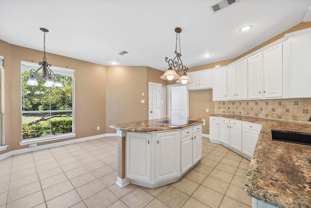 kitchen featuring a center island, white cabinetry, pendant lighting, dark stone countertops, and decorative backsplash