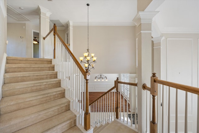 stairway with decorative columns, a notable chandelier, and ornamental molding