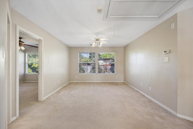 unfurnished room featuring ceiling fan, light carpet, attic access, and a wealth of natural light
