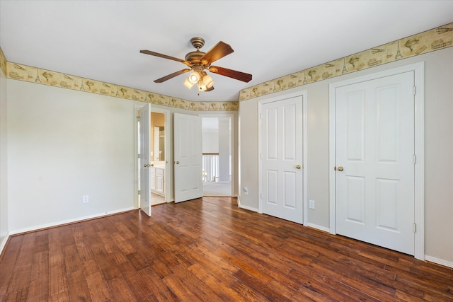 unfurnished bedroom with two closets, dark wood-type flooring, and ceiling fan