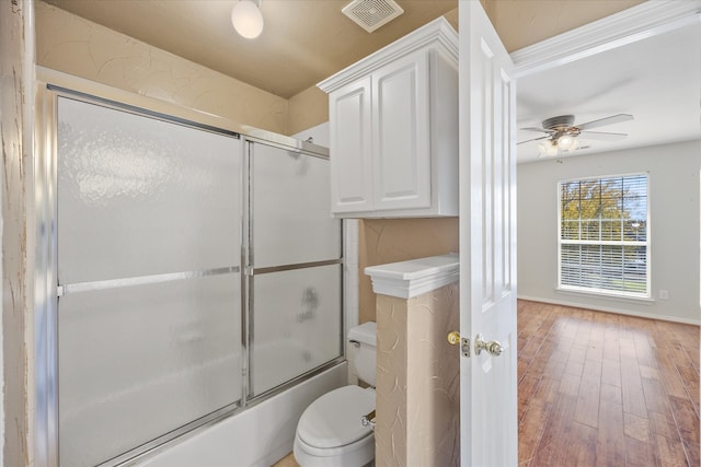 bathroom with toilet, hardwood / wood-style flooring, enclosed tub / shower combo, and ceiling fan