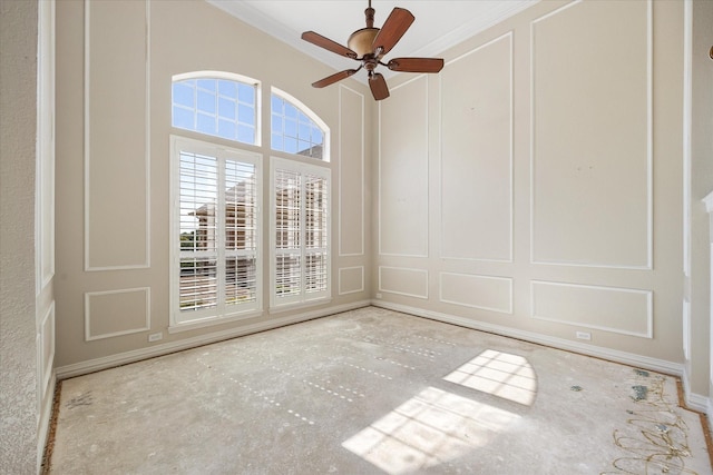 empty room featuring a ceiling fan, baseboards, ornamental molding, and a decorative wall