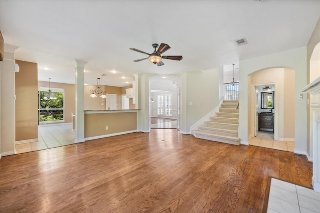 unfurnished living room with visible vents, a ceiling fan, light wood-style floors, and stairs