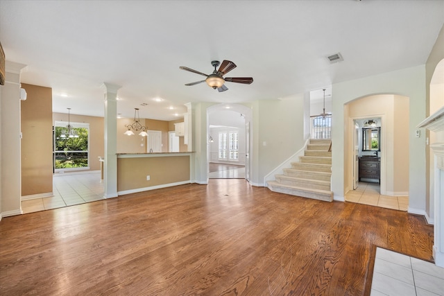 unfurnished living room featuring light hardwood / wood-style flooring and ceiling fan with notable chandelier