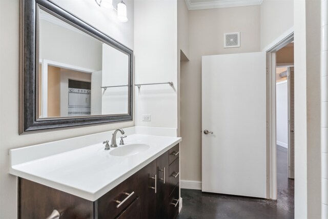 bathroom featuring washer / dryer, vanity, ornamental molding, and concrete floors