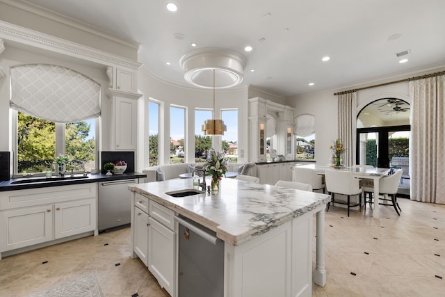 kitchen with a wealth of natural light, a kitchen island with sink, and white cabinetry