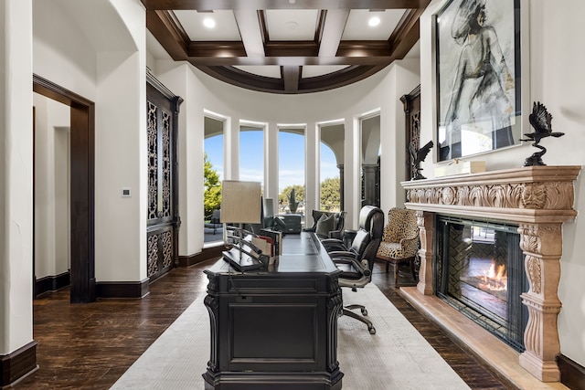 home office featuring a towering ceiling, coffered ceiling, beamed ceiling, and dark hardwood / wood-style flooring