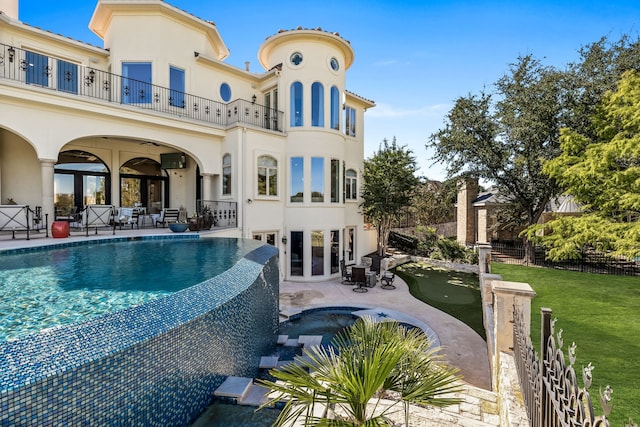 rear view of property with a balcony, french doors, a patio area, and a lawn