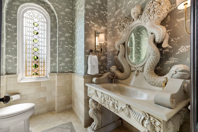 bathroom with toilet, tile patterned floors, and tile walls