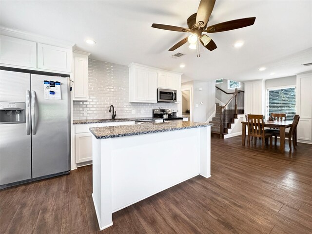 kitchen featuring light stone countertops, appliances with stainless steel finishes, sink, white cabinetry, and dark hardwood / wood-style floors