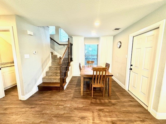 dining room with dark wood-type flooring and a textured ceiling