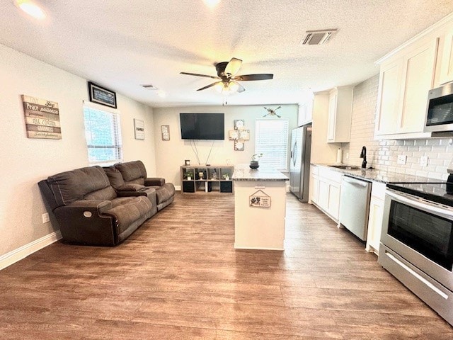 kitchen featuring appliances with stainless steel finishes, sink, a kitchen island, light hardwood / wood-style floors, and white cabinets