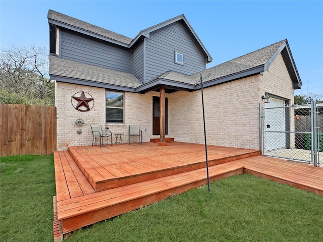 rear view of house featuring a garage, a deck, and a lawn