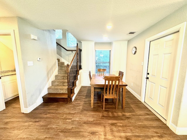 dining space with dark wood-type flooring and a textured ceiling