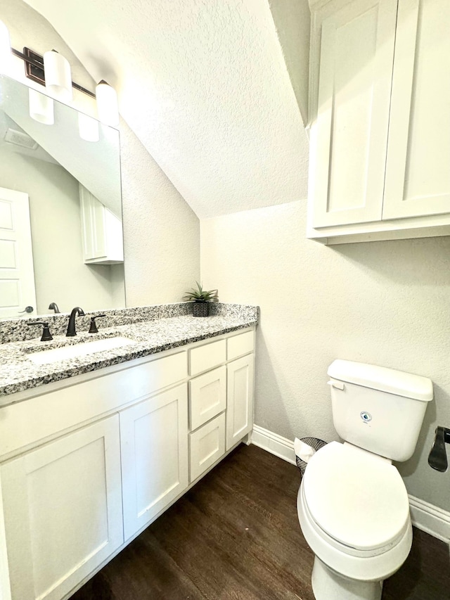 bathroom with vanity, hardwood / wood-style flooring, toilet, and vaulted ceiling