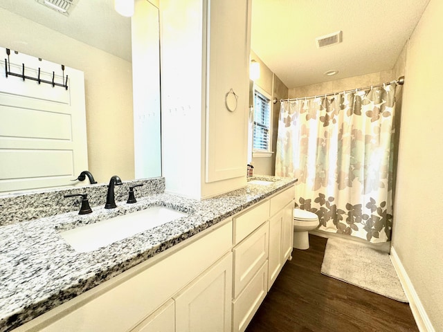 bathroom with toilet, hardwood / wood-style floors, vanity, and a textured ceiling