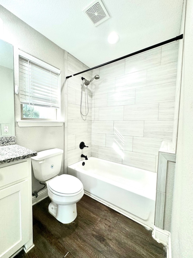 full bathroom with tiled shower / bath, a textured ceiling, hardwood / wood-style flooring, toilet, and vanity