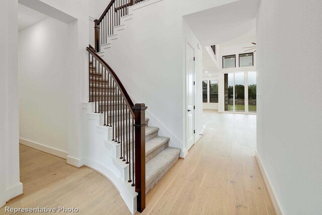 stairs with hardwood / wood-style floors and ceiling fan