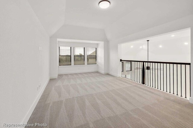 additional living space with light colored carpet and vaulted ceiling