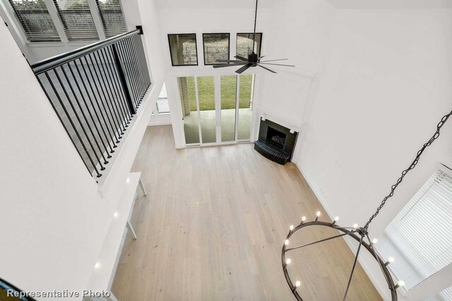 living room with a towering ceiling, ceiling fan with notable chandelier, and light wood-type flooring