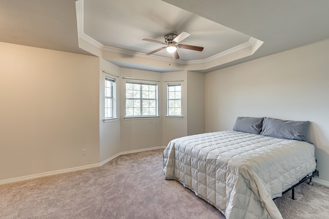 bedroom with ornamental molding, light colored carpet, a raised ceiling, and ceiling fan