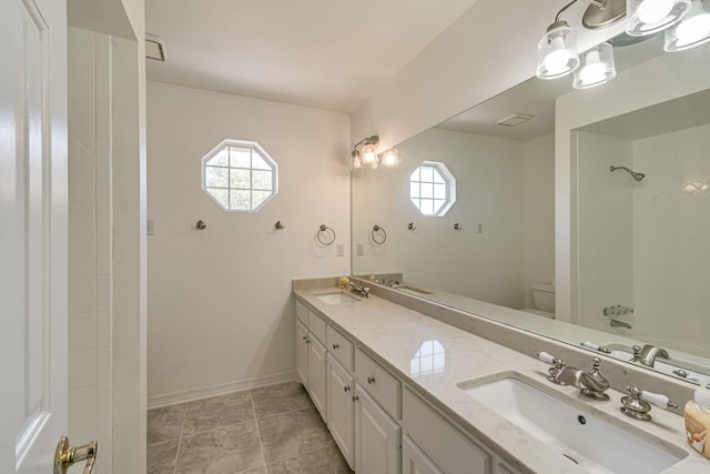 bathroom with toilet, vanity, and tiled shower