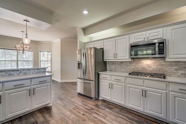 kitchen with dark wood-type flooring, crown molding, appliances with stainless steel finishes, and white cabinets