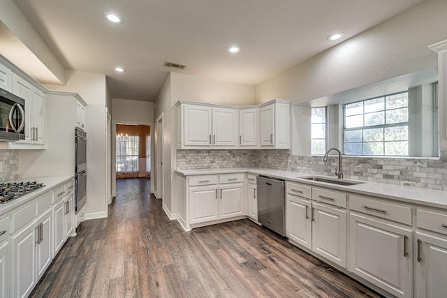 kitchen with white cabinets, stainless steel appliances, sink, and dark hardwood / wood-style flooring