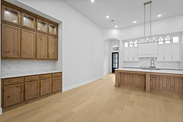 kitchen featuring sink, hanging light fixtures, light hardwood / wood-style flooring, and tasteful backsplash