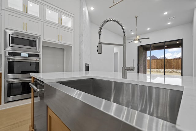 kitchen with white cabinets, light stone countertops, appliances with stainless steel finishes, and sink