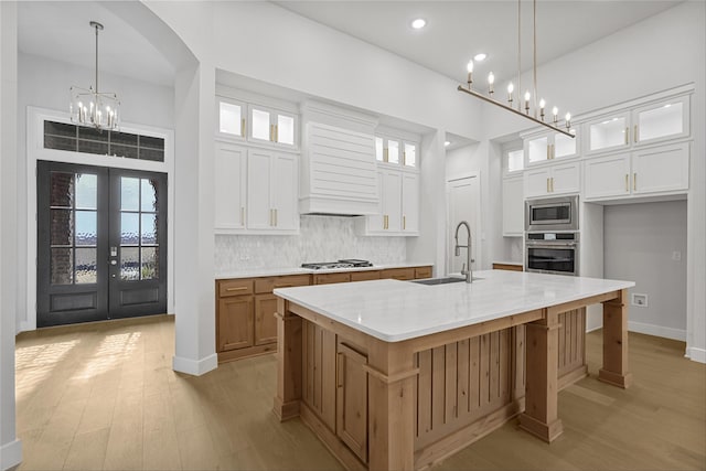 kitchen featuring decorative light fixtures, white cabinets, a large island, and stainless steel appliances