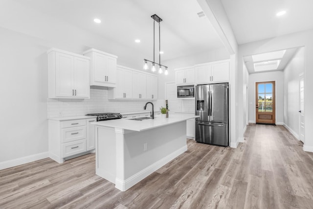 kitchen featuring stainless steel fridge, built in microwave, sink, white cabinets, and hanging light fixtures