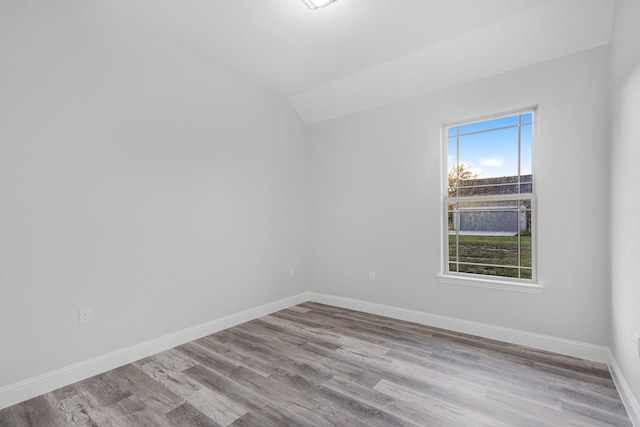 unfurnished room with lofted ceiling and light wood-type flooring