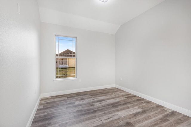 spare room with light hardwood / wood-style flooring and lofted ceiling