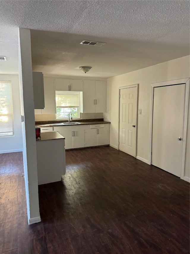 kitchen featuring sink, a textured ceiling, dark hardwood / wood-style flooring, and white cabinets