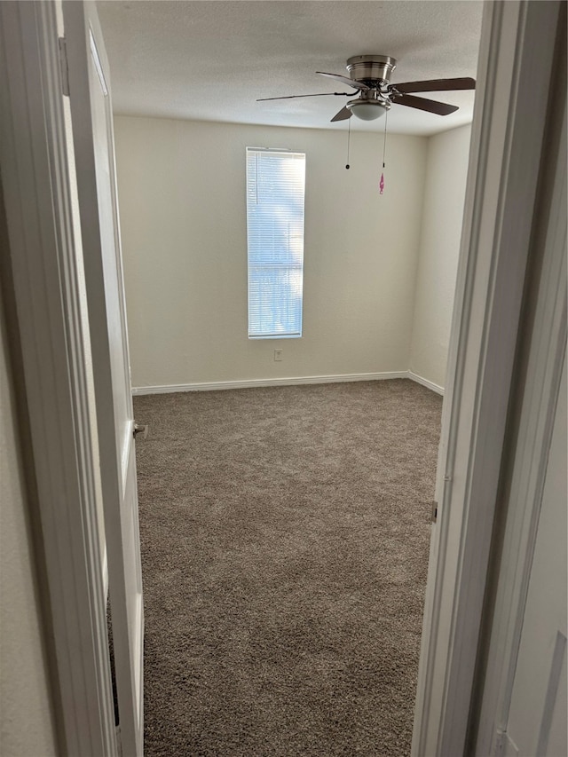 carpeted spare room featuring a textured ceiling and ceiling fan