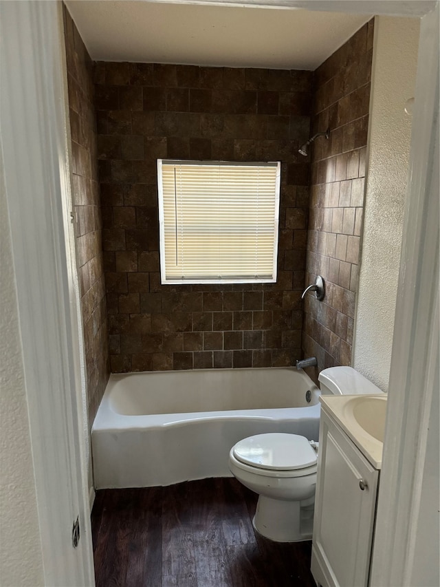 full bathroom with tiled shower / bath, vanity, wood-type flooring, and toilet