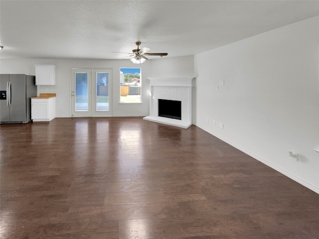 unfurnished living room featuring a textured ceiling, ceiling fan, a fireplace, and dark hardwood / wood-style flooring