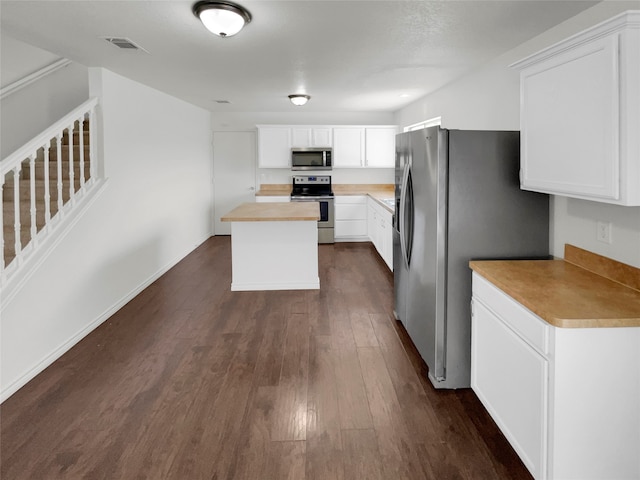 kitchen with butcher block countertops, white cabinetry, stainless steel appliances, and dark hardwood / wood-style floors