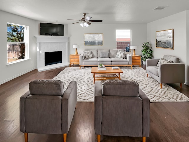 living room featuring ceiling fan, dark hardwood / wood-style floors, and a fireplace